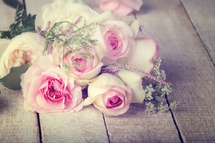 Pink roses arrange for a wedding flower bouquet, set in a wooden floor with greens.